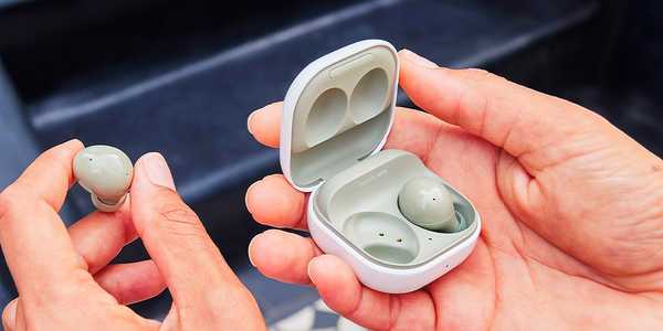 A person holding a pair of olive Samsung Galaxy Buds2. 